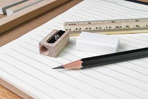 pencil, eraser,ruler with book on woodtable photo