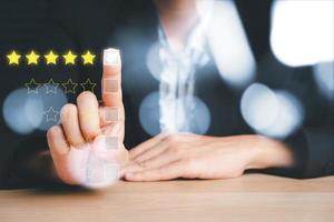 Business woman touching and doing mark to five yellow stars on virtual touch screen.good feedback rating and positive customer review, experience, satisfaction survey, world mental health day concept photo