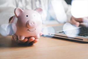 mano de mujer sosteniendo una alcancía en una mesa de madera, concepto de inversión empresarial financiera, negocios, finanzas, inversión, planificación financiera. foto