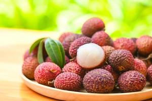 Lychee frui with green leaf on wooden plate background , fresh ripe lychee peeled from lychee tree at tropical fruit Thailand in summer photo