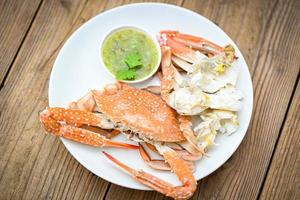 seafood plate fresh crab cooking on white plate background , blue swimming crab meat claw served on a food table - cooking steamed crab with seafood sauce top view photo