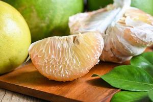 pomelo fruit on wooden background, fresh green pomelo peeled and leaf frome pomelo tree , pummelo , grapefruit in summer tropical fruit  in thailand photo