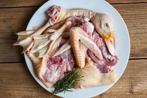 Raw duck breast leg feet wing duck head with spices herb rosemary to cook on white plate, Fresh duck meat for food , poultry meat parts photo