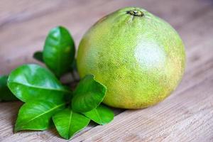 fruta de pomelo sobre fondo de madera, pomelo verde fresco y hoja verde del árbol de pomelo, pomelo, pomelo en verano fruta tropical en tailandia foto