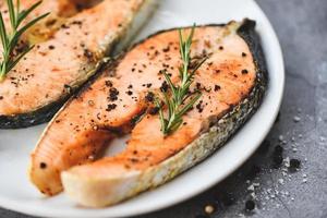 plato de filete de salmón a la parrilla con hierbas y especias romero sobre fondo negro - cerrar filete de salmón cocido filete de pescado marisco foto