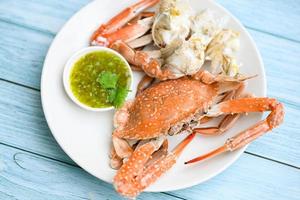 seafood plate fresh crab cooking on white plate background , blue swimming crab meat claw served on a food table - cooking steamed crab with seafood sauce top view photo