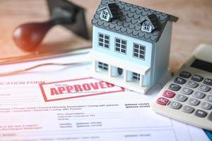 Home loan approved on loan application form paper with rubber stamp calculator and loan house model on table, Loan approval business finance economy commercial real estate investments concept photo