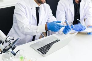equipo de investigación científica está trabajando en laboratorio - investigador médico masculino está haciendo investigaciones con microscopio y computadora portátil en laboratorio bioquímica genética forense análisis de sangre concepto de resultados foto