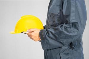 Close up Worker standing in blue coverall holding hardhat photo