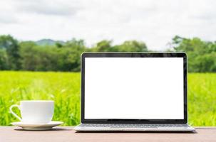 laptop and cofree cup on wood plank agent grass field photo
