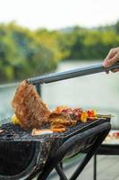 deliciosa carne a la parrilla con humo, barbacoa con verduras al aire libre. barbacoa, fiesta, estilo de vida y concepto de picnic foto