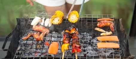 deliciosa carne a la parrilla con humo, barbacoa con verduras al aire libre. barbacoa, fiesta, estilo de vida y concepto de picnic foto