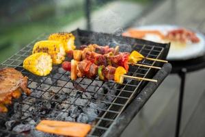 deliciosa carne a la parrilla con humo, barbacoa con verduras al aire libre. barbacoa, fiesta, estilo de vida y concepto de picnic foto