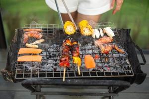 deliciosa carne a la parrilla con humo, barbacoa con verduras al aire libre. barbacoa, fiesta, estilo de vida y concepto de picnic foto