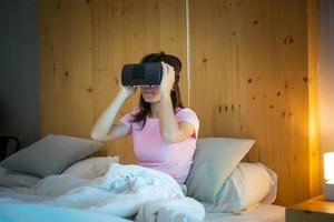 mujer joven con casco de realidad virtual en la cama. vr, tecnología digital futura, juegos, entretenimiento de películas, metaverso, nft y concepto de ciberespacio 3d foto