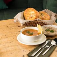 A closeup shot of a soup and appetizers near basket of breads photo