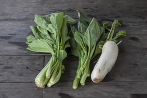 Cantonese or bog choy, Collard greens and Radish are placed on the wooden table in the kitchen. photo