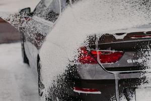 Cleaning car using soap and water pressure. Automobile wash. Transportation washed at local car wash. Vehicle concept. Washing service photo