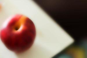 Blurry red apple on white plate. photo