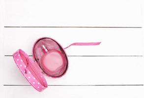 pink perfume bottle on white wooden background. photo