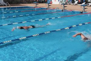 unrecognizable father and son swimming in outdoor sport pool. photo