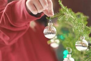 la mano de una niña sosteniendo una bola de navidad. foto