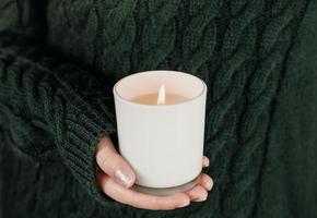 female hand holding white soy candle. photo