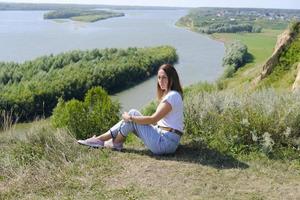 beautiful middle age woman sitting over high river bank. photo