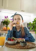 Cute little girl eats fruit salad photo