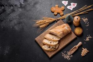 French baguette bread sliced on a wooden cutting board against a dark concrete background photo