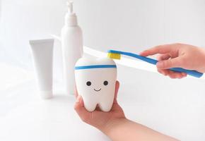 little girl cleaning toy tooth with toothbrush. photo