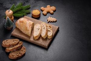 French baguette bread sliced on a wooden cutting board against a dark concrete background photo