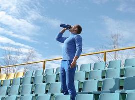 tonificado hombre deportivo bebiendo agua durante un entrenamiento en un estadio. foto