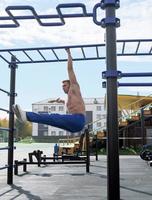 toned man of middle age hanging on a monkey bars photo