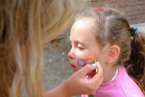 artista pintando un arco iris en la cara de una niña. foto