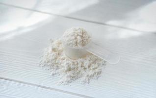 Collagen or protein in powder on white wooden table photo