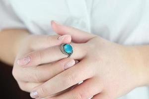 female hands trying on silver ring with blue and white gems. photo
