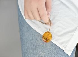 mano femenina sosteniendo una cadena de oro con colgante de ámbar. foto