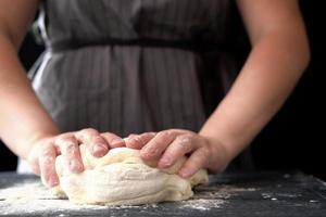 woman chef kneading dough for bread or pizza photo