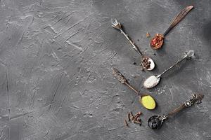 Colourful various spices for cooking in spoons on dark background. photo