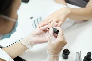 manicurist applying moisturising oil on finger nails photo