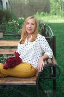 young beautiful woman sitting on a bench near her house photo