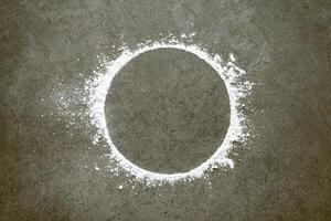 Sprinkled wheat flour circle on stone background. Baking and cooking dough concept. photo