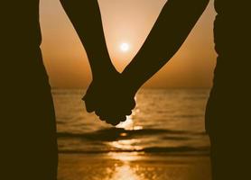 Silhouettes couples holding hands on sunset. photo
