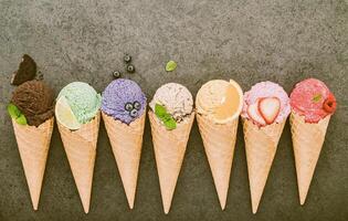 Colección de conos de helado planos laicos sobre fondo de piedra oscura. Cono de helado crujiente en blanco con espacio de copia para el diseño del menú de dulces. foto