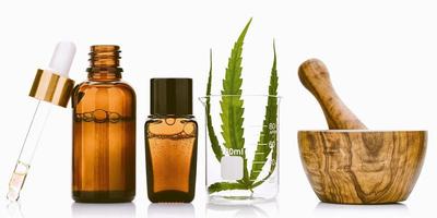 Glass bottles of cannabis oil and hemp leaves isolated on white background.