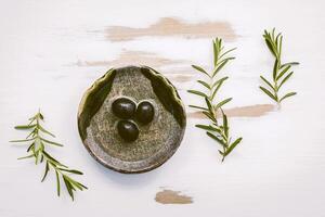 Bowl of extra virgin olive oil with rosemary. Sprigs of rosemary and olive oil set up on white shabby wooden background . Fresh branch of rosemary with bowl of olive oil with flat lay . photo