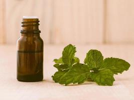 Bottle of mint essential oil on wooden background with selective focus. photo