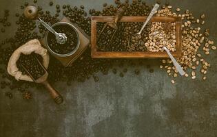 Various of roasted coffee beans in wooden box with manual coffee grinder setup on dark stone background. photo