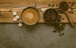 Granos de café tostados con configuración de taza de café sobre fondo de piedra oscura. foto